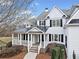 Inviting front exterior with black shutters, white siding, stone accents, a covered porch and well-manicured landscaping at 401 Nichols Dr, Suwanee, GA 30024