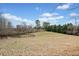 Open land area enclosed by a classic fence, surrounded by mature trees and vegetation at 401 Nichols Dr, Suwanee, GA 30024