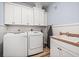 Bright laundry room featuring a washer, dryer, utility sink, lots of cabinet space, and tile floors at 401 Nichols Dr, Suwanee, GA 30024
