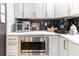 Corner of kitchen featuring stainless steel appliances, gray cabinets with gold hardware, and black and white backsplash at 955 Coleman Sw St, Atlanta, GA 30310