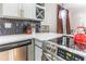 Corner of kitchen featuring stainless steel appliances, light gray cabinets with gold hardware, and black and white backsplash at 955 Coleman Sw St, Atlanta, GA 30310