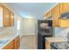 Kitchen with wood cabinets, black appliances and bright dining space at 8051 Trinity Park Dr, Riverdale, GA 30296