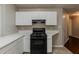 A simple kitchen design featuring white cabinets and black appliances and tiled floors at 964 Chapman Ln, Stone Mountain, GA 30088
