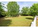 Large backyard with lush green grass, mature trees, flower beds and a wooden deck at 3012 Keeneland Blvd, Mcdonough, GA 30252