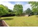 Large backyard with lush green grass, mature trees, and a wooden deck for entertaining at 3012 Keeneland Blvd, Mcdonough, GA 30252