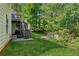 Backyard featuring a staircase, grass, a fire pit, surrounding trees, and a partial view of the home's exterior at 545 Creek Landing Ln, Alpharetta, GA 30005