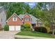 Charming brick home featuring a well-manicured lawn, mature trees, and a two-car garage at 545 Creek Landing Ln, Alpharetta, GA 30005