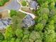 Aerial view of a home nestled among lush trees, a curved driveway, pristine lawn, and luxurious backyard living at 560 Indigo Dr, Roswell, GA 30075