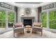 Sitting area features large windows with views of the surrounding landscaping and a stone fireplace at 560 Indigo Dr, Roswell, GA 30075