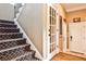 Staircase with patterned carpet runner and a view into the front entry with a glass door at 1114 Waterford Green Pt, Marietta, GA 30068