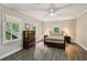 Bedroom features a ceiling fan, tan walls, wood look flooring, and two windows with views of greenery at 1275 Smokehouse Trl, Cumming, GA 30041