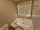 Comfortable bathroom with soaking tub, window, and light fixtures at 71 Streamview Trl, Douglasville, GA 30134
