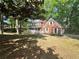 Two story red brick home with white trim and shutters surrounded by mature trees at 894 Oak Rd, Lawrenceville, GA 30044