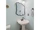 Charming powder room with a pedestal sink, decorative mirror, and light blue walls at 150 Park Creek Dr, Alpharetta, GA 30005