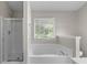 Bathroom featuring a shower, large bathtub with faucet, and a window for natural lighting at 110 Slate Ridge Ln, Loganville, GA 30052