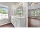 Bright bathroom with double sink vanity, large mirror, wood-look floors, and natural light at 110 Slate Ridge Ln, Loganville, GA 30052