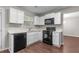 Modern kitchen featuring white cabinets, black appliances, and wood-look flooring at 110 Slate Ridge Ln, Loganville, GA 30052