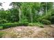 Spacious backyard with a stone patio and gravel area, surrounded by lush greenery, perfect for outdoor entertaining at 2980 Milford Sw Trl, Marietta, GA 30008