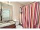 Bright bathroom with a granite-topped vanity, large mirror, and a colorful striped shower curtain at 3812 Maclaren Dr, Clarkston, GA 30021
