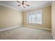 Spacious bedroom with plush carpeting, a ceiling fan, and a large window offering plenty of natural light at 10462 Bent Tree Vw, Duluth, GA 30097