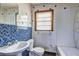 Well-lit bathroom featuring a sink, toilet, window, tub, and blue accent tile at 1815 Windsor Sw Dr, Atlanta, GA 30311