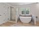 Modern bathtub in a spacious bathroom featuring designer tile, a large window, and an adjacent glass enclosed shower at 4030 Scenic View Ct, Cumming, GA 30028