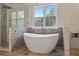 Modern bathtub in a spacious bathroom featuring designer tile, a large window, and an adjacent glass enclosed shower at 4030 Scenic View Ct, Cumming, GA 30028