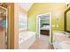 Bright bathroom featuring a garden tub, separate shower, and light tile flooring leading into the bedroom at 20 Queensland Ln, Covington, GA 30016