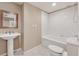 Elegant bathroom featuring a pedestal sink, framed mirror, tiled walls and flooring, and a bathtub with shower at 1632 Chadwick Ridge Dr, Lawrenceville, GA 30043