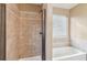 Updated bathroom shower with tile surround next to a white tub under a window at 2426 Windridge Dr, Conyers, GA 30013