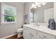Bathroom with a white vanity, framed mirror, and a window providing natural light at 7545 Brookwood Way, Cumming, GA 30041