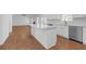 A bright, modern kitchen featuring an island with quartz countertops, stainless steel appliances, and beautiful hardwood floors at 552 Steels Bridge Rd, Canton, GA 30114