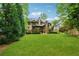 Expansive green backyard and back exterior of the home, surrounded by mature trees and lush landscaping at 2551 Raintree Ne Dr, Atlanta, GA 30345