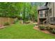 Landscaped backyard featuring a stone wall, green grass, trees and a garden at 2551 Raintree Ne Dr, Atlanta, GA 30345