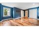 Bedroom featuring hardwood floors, blue walls, built in shelf, and white baseboard trim at 10192 Shallowford Rd, Roswell, GA 30075