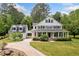 Charming two-story white farmhouse with a large covered front porch and meticulously maintained landscaping at 10192 Shallowford Rd, Roswell, GA 30075
