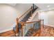 Elegant staircase featuring decorative iron railing, carpeted steps and hardwood flooring at 10192 Shallowford Rd, Roswell, GA 30075