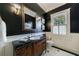 Elegant bathroom featuring a dark vanity with marble countertop and modern fixtures, with a bright shuttered window at 3 Demorest Ne Ave, Atlanta, GA 30305