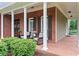 Covered front porch with brick flooring, columns, and comfortable seating area at 4592 Planters Hill Dr, Powder Springs, GA 30127