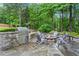 Stone patio with outdoor kitchen, built-in grill and fire pit surrounded by Adirondack chairs at 4592 Planters Hill Dr, Powder Springs, GA 30127