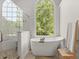 Bright bathroom featuring a glass shower and soaking tub under a large window at 5620 Preserve Cir, Johns Creek, GA 30005