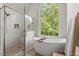 Bright bathroom with glass shower and soaking tub under a large window at 5620 Preserve Cir, Johns Creek, GA 30005