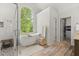 Bright bathroom features a soaking tub under a large window, a glass shower, and wood-look flooring at 5620 Preserve Cir, Johns Creek, GA 30005