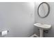 Half bath features a pedestal sink, oval mirror, and modern fixtures at 5654 Lawley Dr, Alpharetta, GA 30022