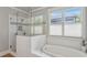 Modern bathroom featuring a glass shower with subway tile, a soaking tub, and natural light from the nearby windows at 519 2Nd Ave, Decatur, GA 30030