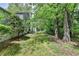 View of the home's large backyard with mature trees and patio area at 655 Barrington Way, Roswell, GA 30076
