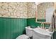 Charming powder room featuring green wainscoting, floral wallpaper, and a white vanity at 4257 Edgewater Nw Dr, Kennesaw, GA 30144