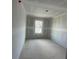 A bare bedroom under construction awaiting finishing touches, with bare walls and floors and a window at 5106 Arista Dr, Douglasville, GA 30135