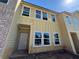 New townhome featuring a light yellow facade with white trimmed windows and a brick accent wall at 5106 Arista Dr, Douglasville, GA 30135