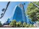 Modern glass high-rise exterior surrounded by lush green trees and vibrant cityscape views at 3344 Peachtree Ne Rd # 3601, Atlanta, GA 30326